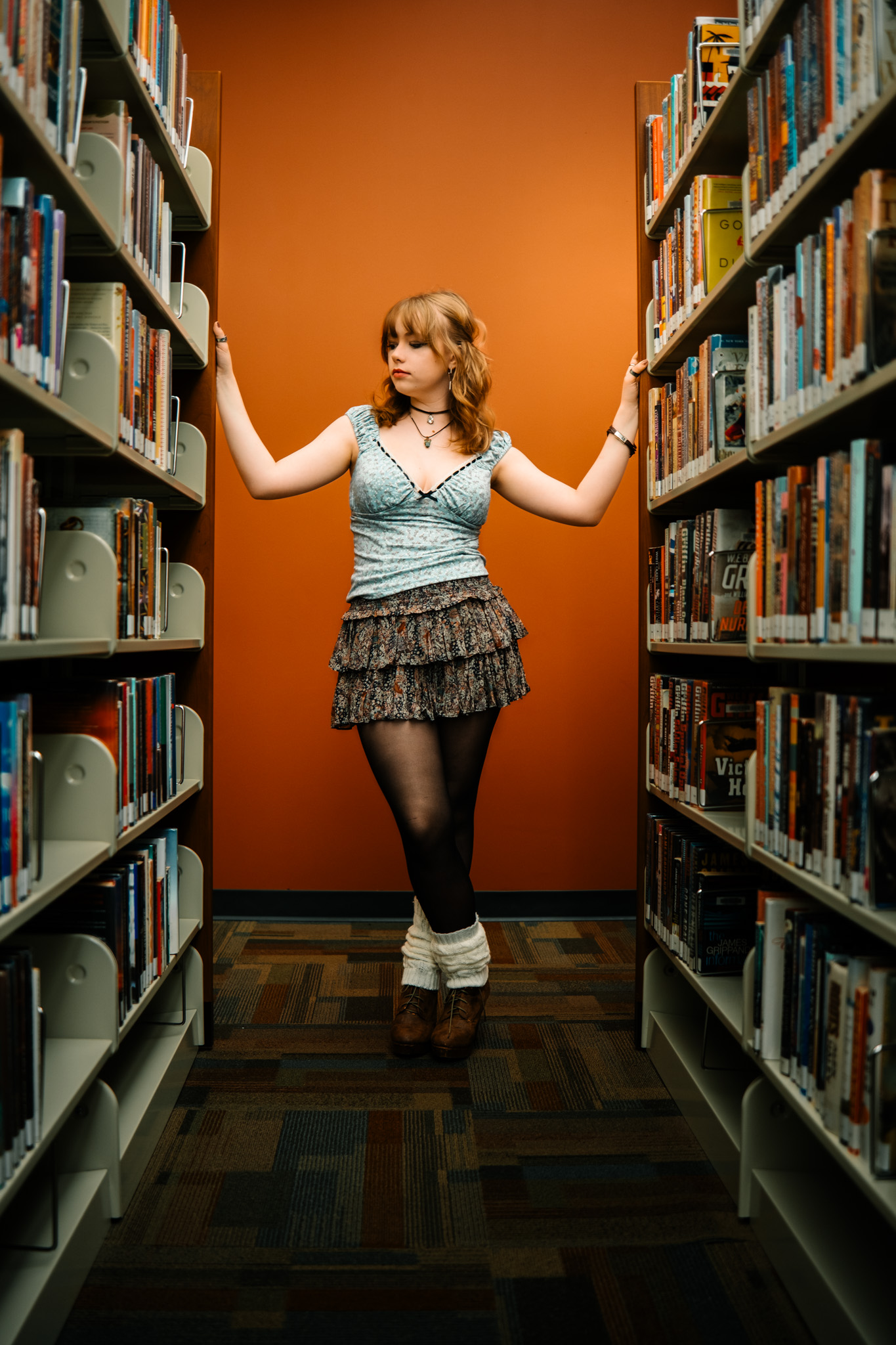 Editorial portrait in library with orange wall